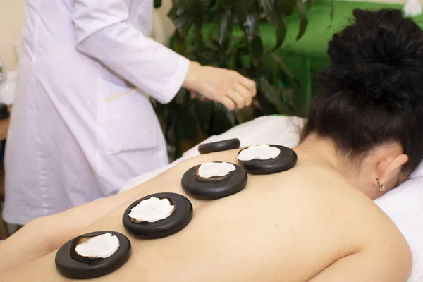 Dívka na kamenné terapii, masáž horkými kameny. Restorativní procedura pro tělo i duši - masáž kamenem — Stock fotografie