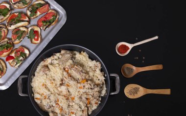 Top view of Indian traditional dishes and appetizers: chicken curry, pilaf, naan bread, samosas, paneer, chutney on rustic background. Flat lay