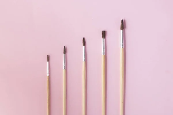 Cinco pinceles de pintura sobre papel rosa, concepto de estadísticas de crecimiento plano — Foto de Stock