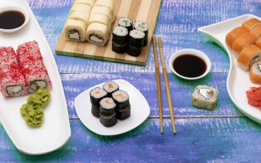 Salamura zencefil, avokado, salatalık, soğan, nori ve susamlı vejetaryen suşi çörekleri mavi ahşap arka planda. Yukarıdan, yukarıdan.