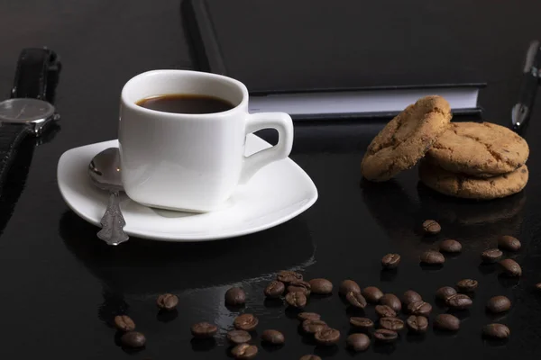 Coffee background with beans and white cup. Dark atmosphere and copy space. Oatmeal cookies and notebook — Stock Photo, Image