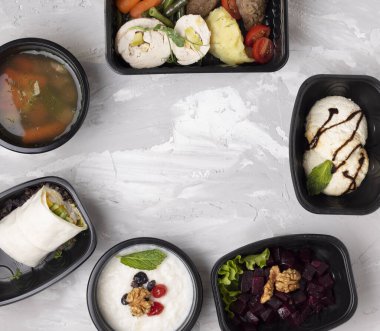 Lezzetli kahvaltı ve öğle yemeği beton masadaki siyah plastik kaplarda. Metin için düz yatış ve yer