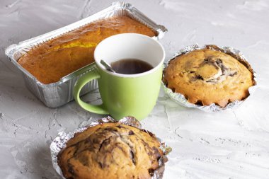 Bardakta soğuk çay ve folyoda üç kek. Pastaların arkaplanı