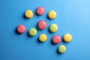Yukarıdan mavi arka planda kek makaronu. Tatlıda renkli kurabiyeler, düz uzanma