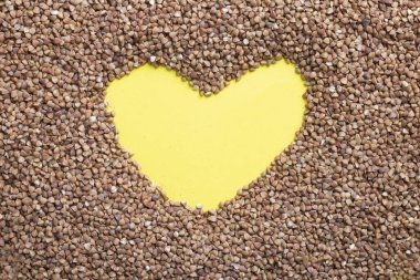 Sarı arka planda kalp şeklinde kurutulmuş karabuğday, sağlıklı beslenme. Üst görünüm ve kopyalama alanı