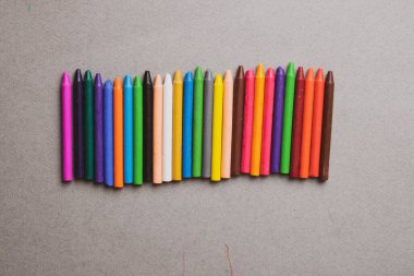 Gri kağıt üzerinde renkli balmumu boya kalemleri. Üst görünüm