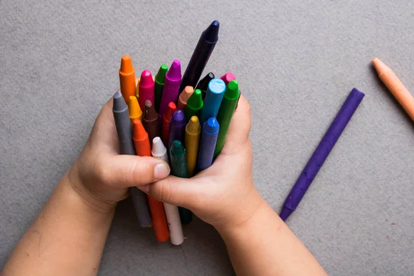 Set of wax crayons in hands, top view and place for text.