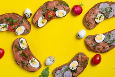 Somonlu altı ekmek, bıldırcın yumurtası ve sebze. Sarı kağıt üzerinde, üst manzara. Sarı kağıt