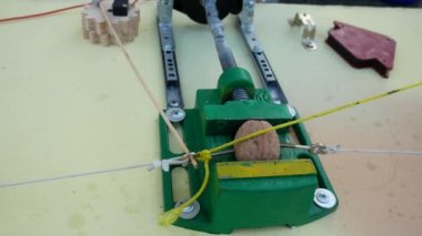 Rube Goldberg Makinesi. Mengene fındığı sıkıyor ve ikiye ayırıyor. Lastik ipi çeker..