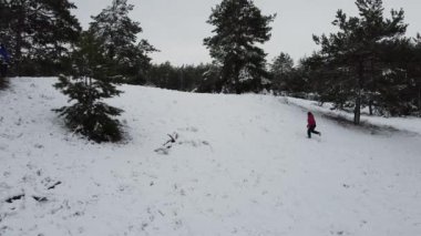 A woman runs on a snowy hillock. View from above. Snowy forest