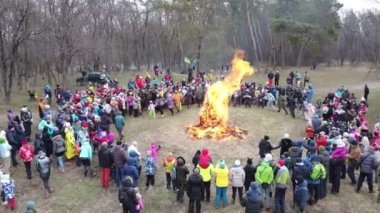 Çocuklar ve yetişkinler Shrovetide festivalinde şenlik ateşinin etrafında dans ediyorlar..