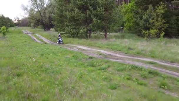フィールドと森の間の未舗装の道路に沿って元スクーターやバイクに乗っている少女と子供 — ストック動画
