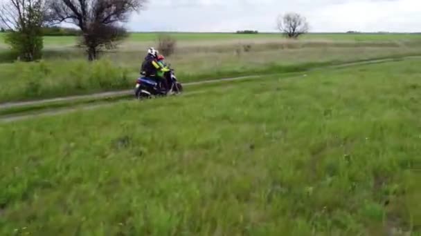 Dívka a dítě jezdí na moto skútru nebo motocyklu po prašné cestě mezi polemi.Letecké, drone záběry.
