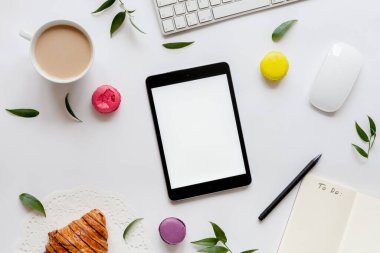 Tablet, klavye, bir fincan kahve, çiçekler ve kekler, üst manzara. Beyaz bahar arkaplanı.