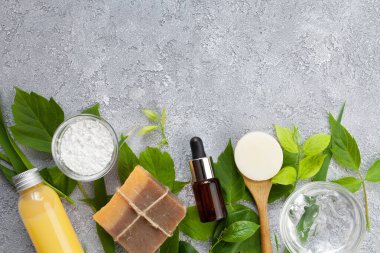 Vücut ve yüz için doğal kozmetik ürünler: sabun, aljinat maskesi, aloe vera jeli, gri arka planda serum, üst görünüm
