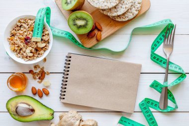 Diyet yemekleri: müsli, bal, fındık, kivi ve mısır gevreği, zencefil ve avokado. Diyet konsepti. Tahta beyaz arkaplan, üst görünüm