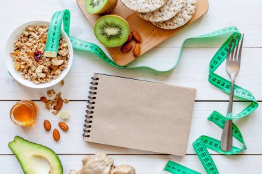 Diyet yemekleri: müsli, bal, fındık, kivi ve mısır gevreği, zencefil ve avokado. Diyet konsepti. Tahta beyaz arkaplan, üst görünüm