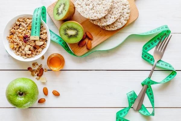 Diyet yemekleri: müsli, bal, fındık, kivi ve mısır gevreği, zencefil ve avokado. Diyet konsepti. Tahta beyaz arkaplan, üst görünüm