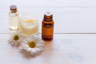 Hafif ahşap arka planda papatya özlü saf cilt bakımı kozmetiği.