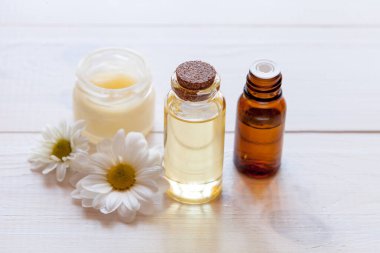 Doğal malzemeli cilt bakım ürünleri: yağ, serum, beyaz ahşap üzerine yüz kremi, üst görünüm