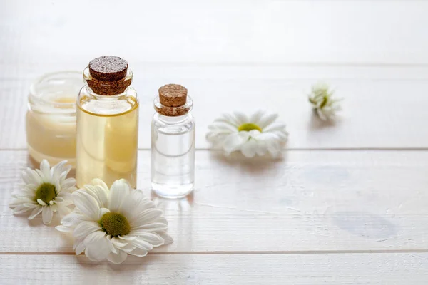 Hafif ahşap arka planda papatya özlü saf cilt bakımı kozmetiği.