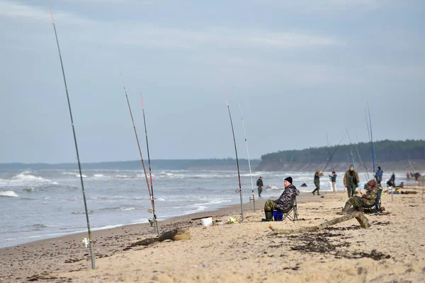 Pescadores com um poste de pesca sentado na costa — Fotografia de Stock