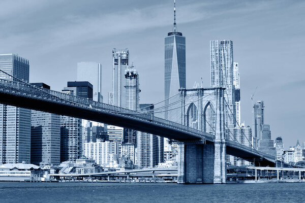 Brooklyn Bridge is a hybrid cable-stayed/suspension bridge in New York City and is one of the oldest bridges in the United States, Black and white blue toned