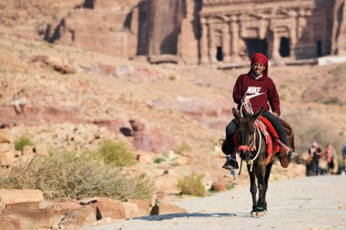 Petra, Ürdün - 18 Şubat 2020. Arap Bedevi Rehberi Ürdün 'ün Petra şehrinde at sürüyor. Petra, ülkenin UNESCO Dünya Mirası listesine girmesini sağladı..