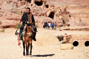 Petra, Ürdün - 18 Şubat 2020. Arap Bedevi Rehberi Ürdün 'ün Petra şehrinde at sürüyor. Petra, ülkenin UNESCO Dünya Mirası listesine girmesini sağladı..