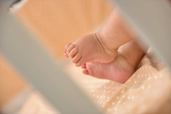 Feet of baby in the crib in natural light