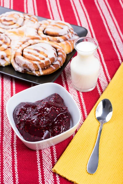 Snail cake with jam and milk on the table in natural light