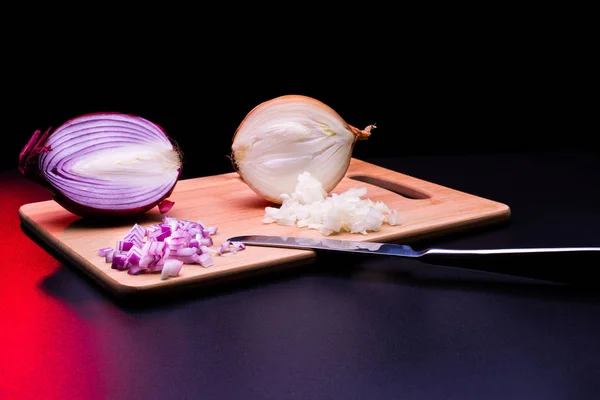 Red and white onion cut and all on a wooden bottom in black background