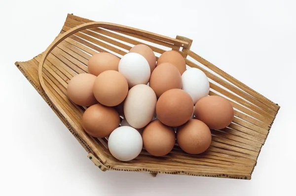Chicken eggs in a basket of different colors shades as background — Stock Photo, Image