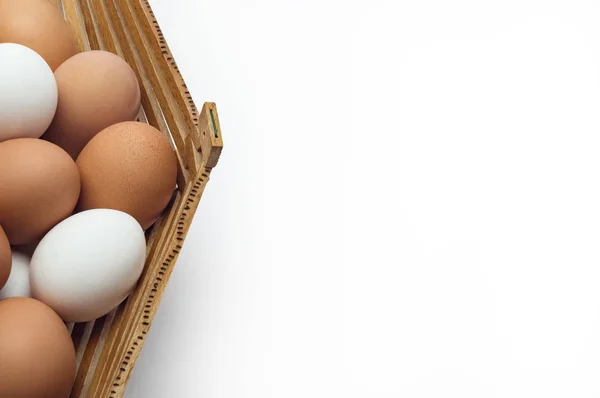 Chicken eggs in a basket of different colors shades on the left edge — Stock Photo, Image