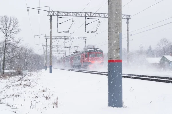 El tren eléctrico de pasajeros se mueve durante una ventisca en invierno — Foto de Stock