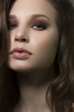 Güzel esmer model kadın yüzü, yeşil gözleri ve mükemmel makyajı var. Güzel, esmer bir kızın portresi. Doğal dudakları, dumanlı gözleri, kalın kaşları var. Açık tenli bir kadın yüzü. Yakın plan..