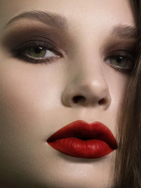 Közelkép a gyönyörű nő tisztaság arcát sötét fekete füstös szemek smink, piros teli ajkak. Szexi modell tiszta fényes bőrrel, tisztaság arcbőrrel — Stock Fotó