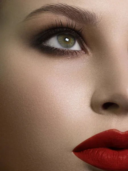 Ein halbes Schönheitsporträt mit wunderschönem modischem Abend-Make-up, schwarzen Raucheraugen und extrem langen Wimpern. Rote Lippenstifte auf den Lippen. Kosmetologie und Wellness-Gesichtspflege — Stockfoto