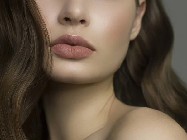 Närbild av kvinnans läppar med mode naturliga beige läppstift makeup. Makro sexig blek läppglans make-up. Skonsam ren hud och vågigt brunett hår. Kosmetologi, Spa, ökning av läppar — Stockfoto