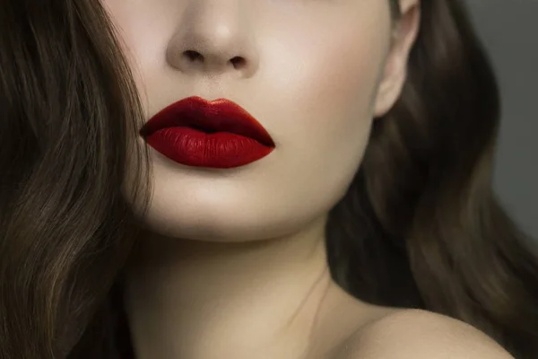 Close-up of woman's lips with fashion natural red lipstick makeup. Macro sexy pale lipgloss make-up . Gentle pure skin and wavy brunet hair. Cosmetology, Spa, increase in lips — ストック写真