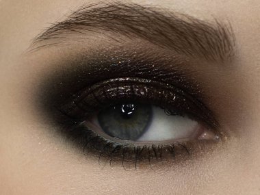 Zarif, yakın plan, koyu siyah göz farı olan kadın gözü. Güzel bir kadının yüzünün makro görüntüsü. Sağlık, kozmetik ve makyaj. pürüzsüz güzel kaşlar ve kirpiklerle