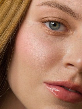 Yarı yüzü kızıl saçlı, çilli ve uzun saçlı. Temiz cilt, açık makyaj, seksi görünüş. Dudaklarda ruj izi, gözlerde kalem, yanaklarda hafif kızarıklık. Spa ve kozmetoloji