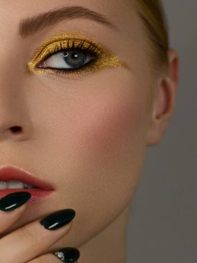 Yarı güzel, yakın plan seksi genç kadın akşamı koyu kirpikleri boyalı ve altın kaplamalı, makyaj sanatçısı kozmetik güzellik salonu spa 'sı. Uzun yeşil tırnaklar, temiz cilt ve doğal çıplak dudaklar..