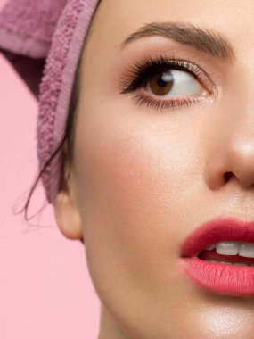 Mükemmel ciltli yarım yüzlü kız. Kadın şaşkınlıkla kameraya bakar, ağzını açar. Gençlik ve cilt bakımı konsepti. Ekstra uzun kirpikler, göz kalemi ve pembe rujlu seksi dolgun dudaklar.