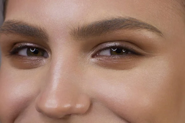 Close-up portrait of the cleanliness of the face of a beautiful woman with dark black smoky eye makeup. Sexy model with clean shiny skin, a clean face, thick eyebrows and extremely long eyelashes — Stock Photo, Image