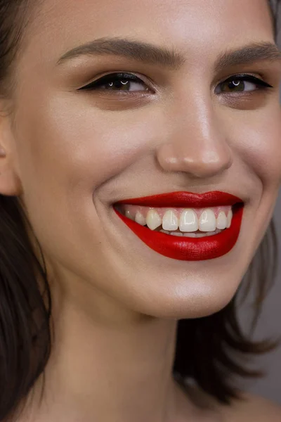 Κοντινό πορτρέτο της καθαριότητας του προσώπου μιας όμορφης γυναίκας με eyeliner, κόκκινα πρησμένα χείλη. Ένα σέξι μοντέλο με καθαρό λαμπερό δέρμα, πυκνά φρύδια και πολύ μακριές βλεφαρίδες. χαμόγελο με λευκά δόντια — Φωτογραφία Αρχείου