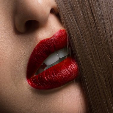 Kırmızı dudak parlatıcısı ve saçları olan seksi kadın dudaklarını kapat. Temiz cilt ve berrak dudak hatları, modaya uygun rujla çizilmiş. Beyaz dişler ve gülücükler stamotoloji, spa ya da kozmetoloji için güzel