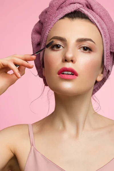 Nahaufnahme einer schönen Frau mit natürlichem Make-up und sauberer Haut mit einem Handtuch auf dem Kopf. kämmt ihre dicken Augenbrauen. extrem lange Wimpern, rosa Lippenstift auf den Lippen. Kosmetik und Wellness — Stockfoto