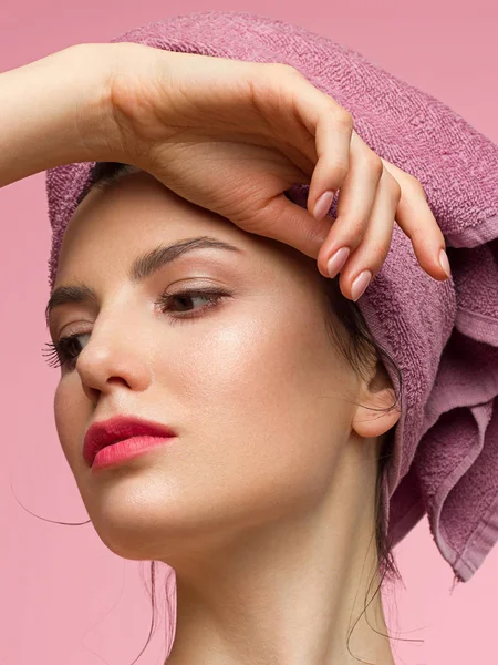 Temiz mükemmel bir cilde sahip güzel genç bir kadın. Doğal çıplak makyaj ve yüzüne dokunarak güzellik modeli Portresi. Spa, cilt bakımı ve sağlıklı yaşam. Yakın çekim, pembe arka plan, copyspace.