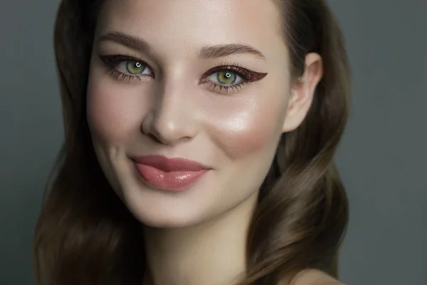 Krásný brunet model žena tvář se zelenýma očima a perfektní make-up, aby úsměv na kameru. Portrét krásy s přirozenými rty a víčky, husté obočí. Žena tvář s čistou pletí close-up. — Stock fotografie